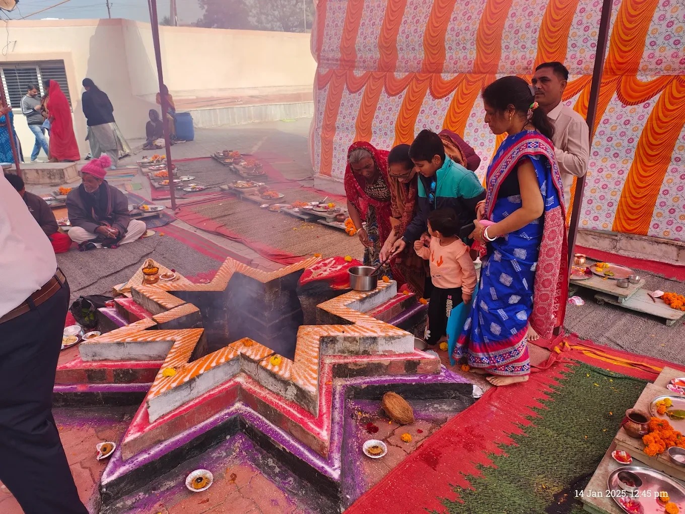 A yagya (fire ritual) in progress at Surya Mandir Borsad, with a family offering ahuti