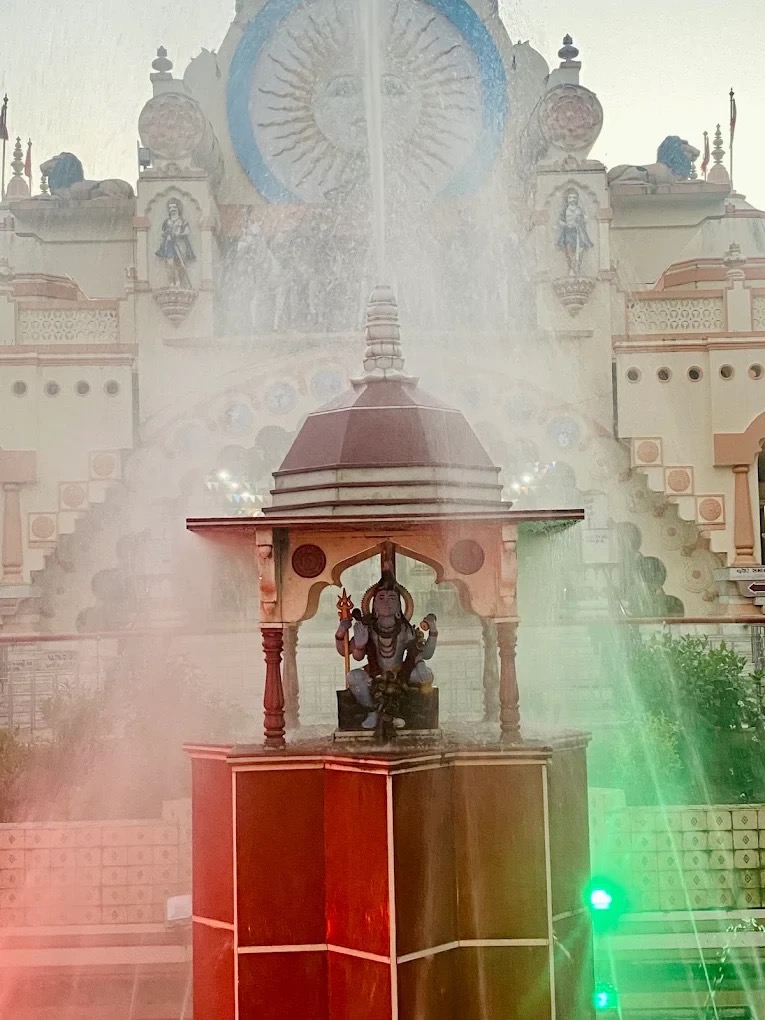 Colourful fountain with a Hanuman shrine in front of the temple